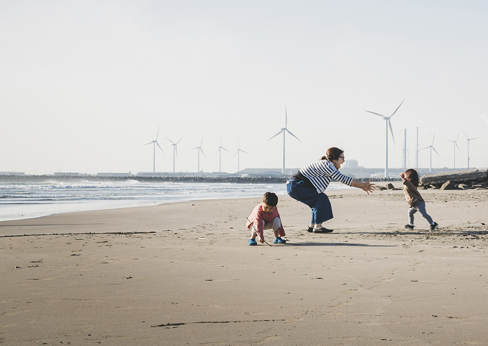 Family on beach with wind turbines in the background