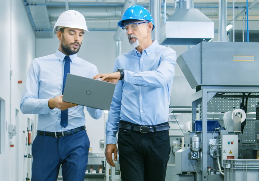 Two engineers walking through an industrial manufacturing facility.