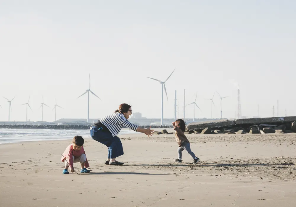 Family on a beach with wind turbines in the background