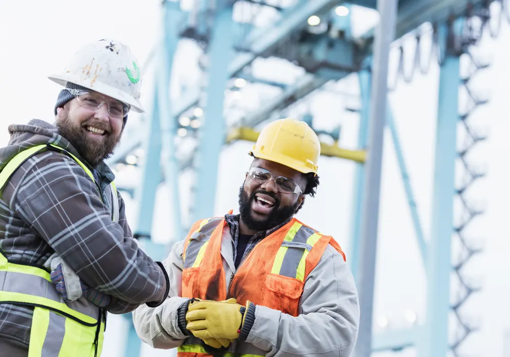 Two laughing workers at a busy port